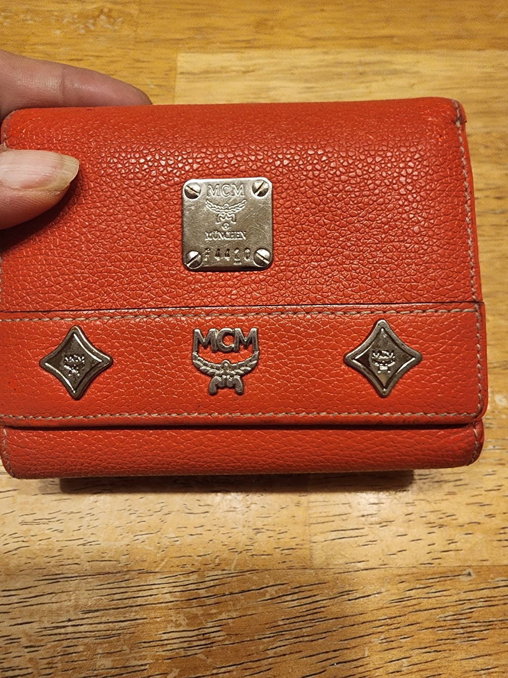 vibrant coral-orange textured leather trifold wallet features the iconic MCM